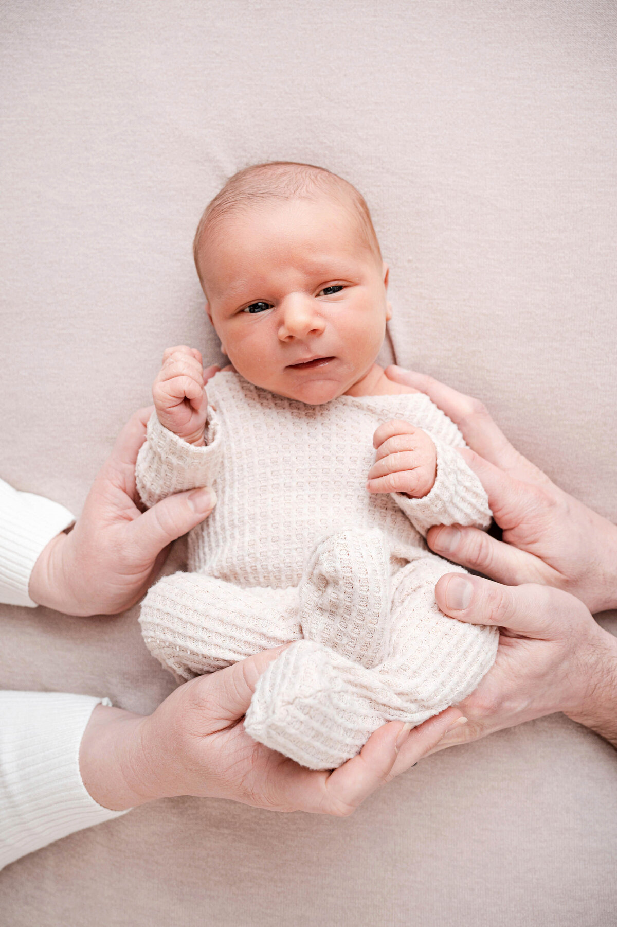 little baby with parents hands on him during gentle caring newborn session