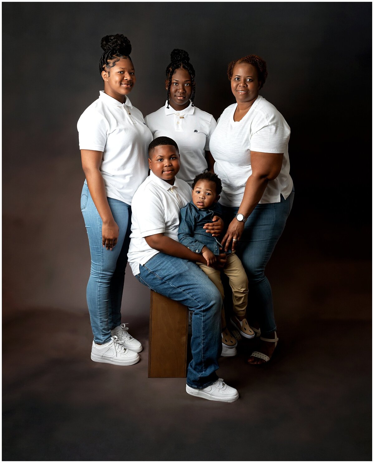 A loving family of five, smiling in a beautiful family studio portrait session.