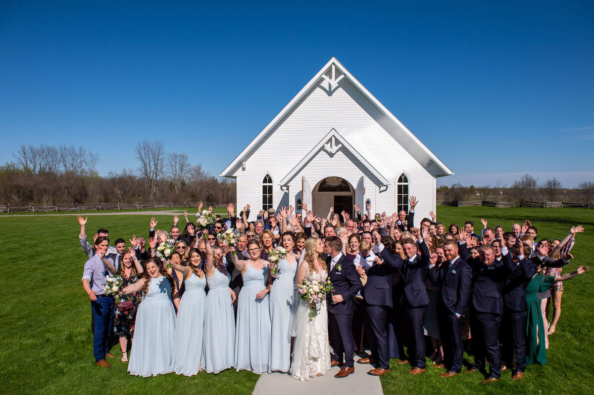 a large group photo showing the bride, groom, their wedding party and all their guests taken outside the Ceremony House at Stonefields Estate in Ottawa