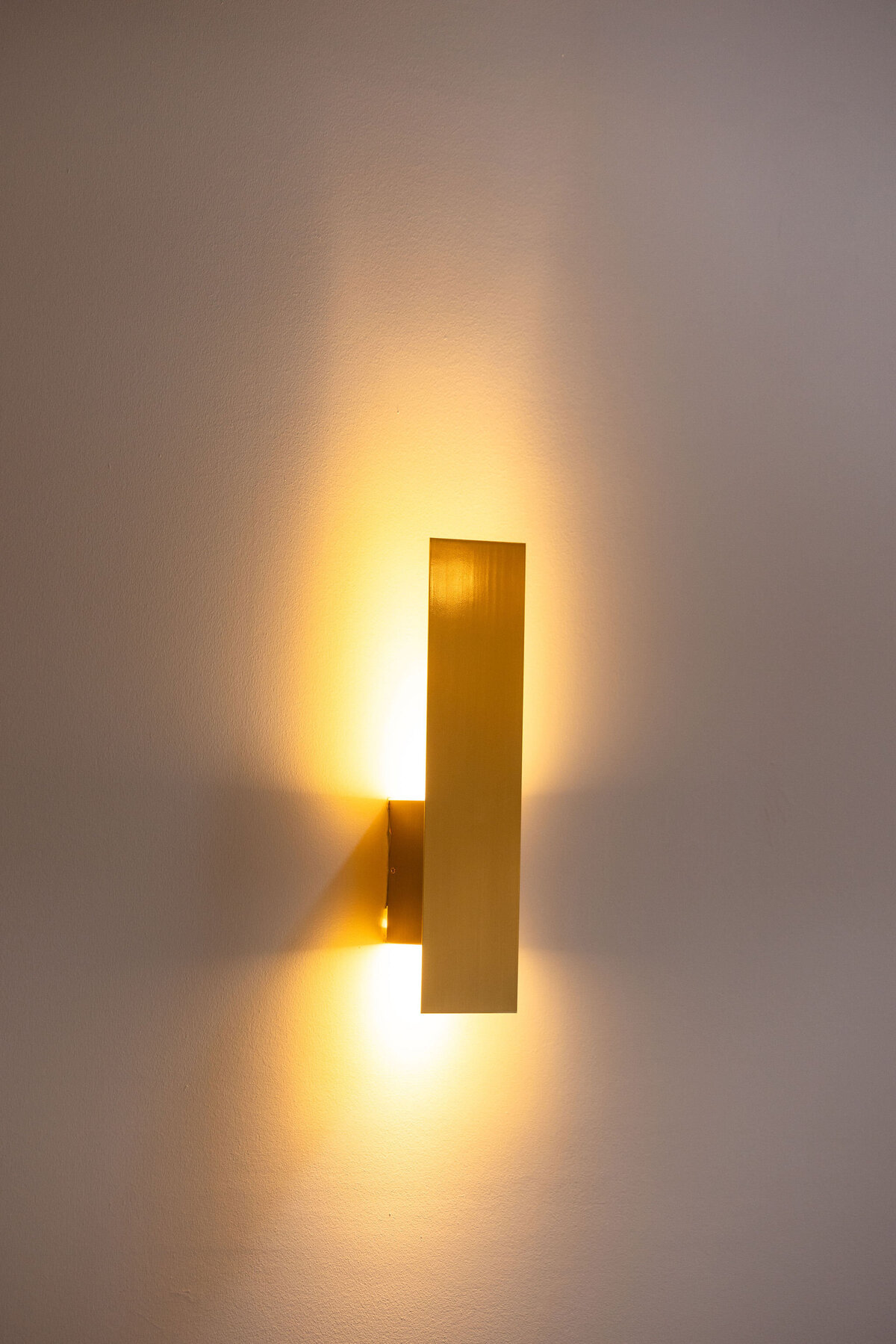 Close-up of the brassy-toned timeless sconce scattered throughout the Locus and Happy Hour space, adding elegance and attention to detail within original exposed industrial ceilings and natural light