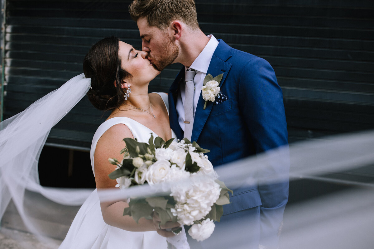 Bride and groom kissing under a veil at the Pittsburgh Opera.