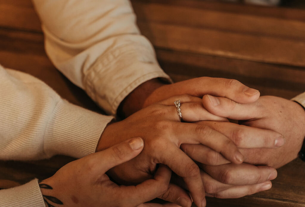 Couple holding hands with engagement ring