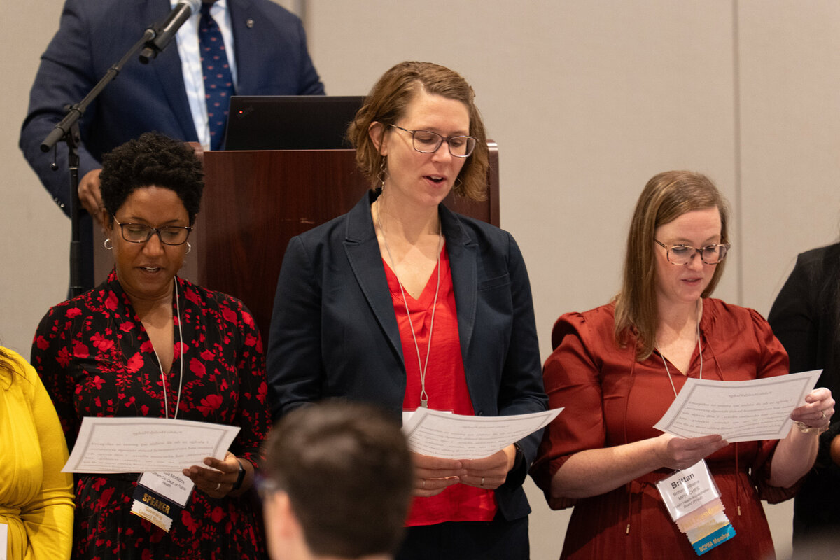 a group of people standing together reading off of papers 