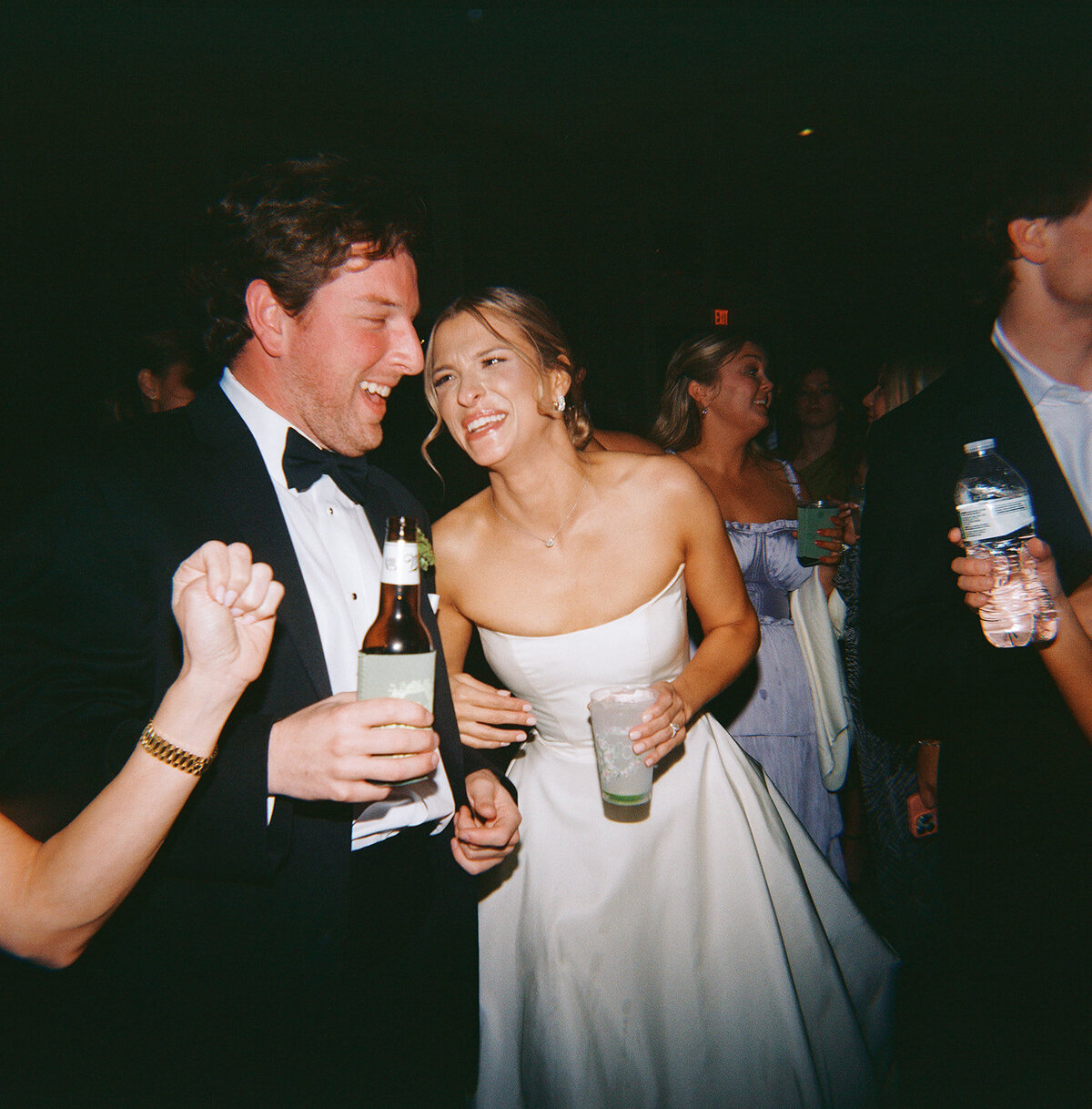 Bride and groom laughing and dancing together at their wedding reception at Burritt on the Mountain, surrounded by guests holding drinks.