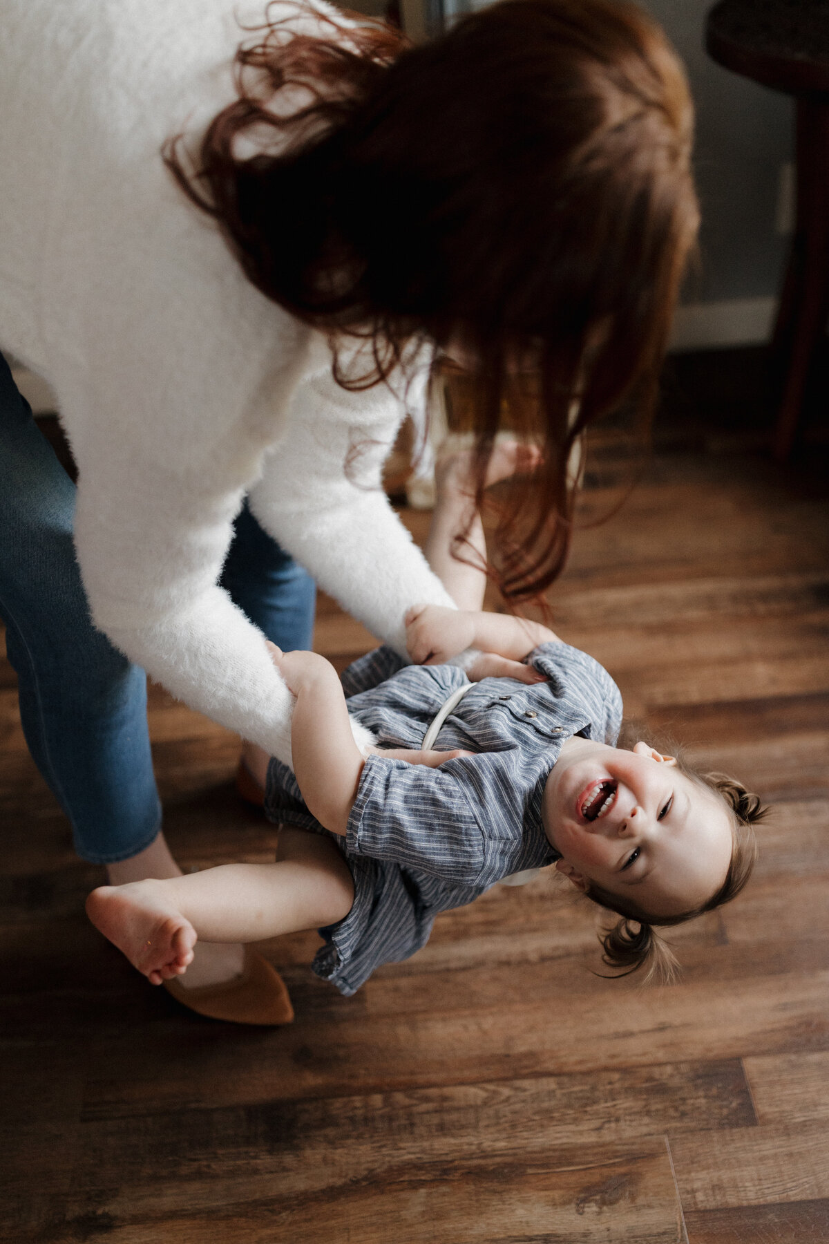 A mother playing with her child indoors, capturing candid wedding photography emotions in a warm and intimate setting.