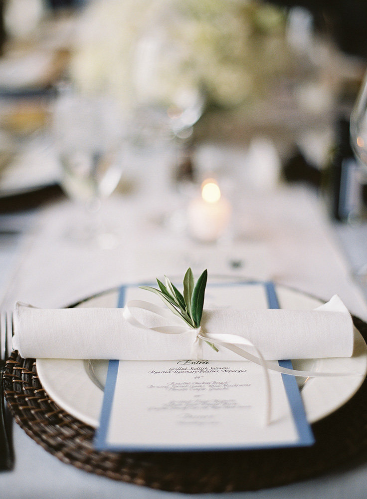 rolled napkin with sprig of greenery with blue menu card
