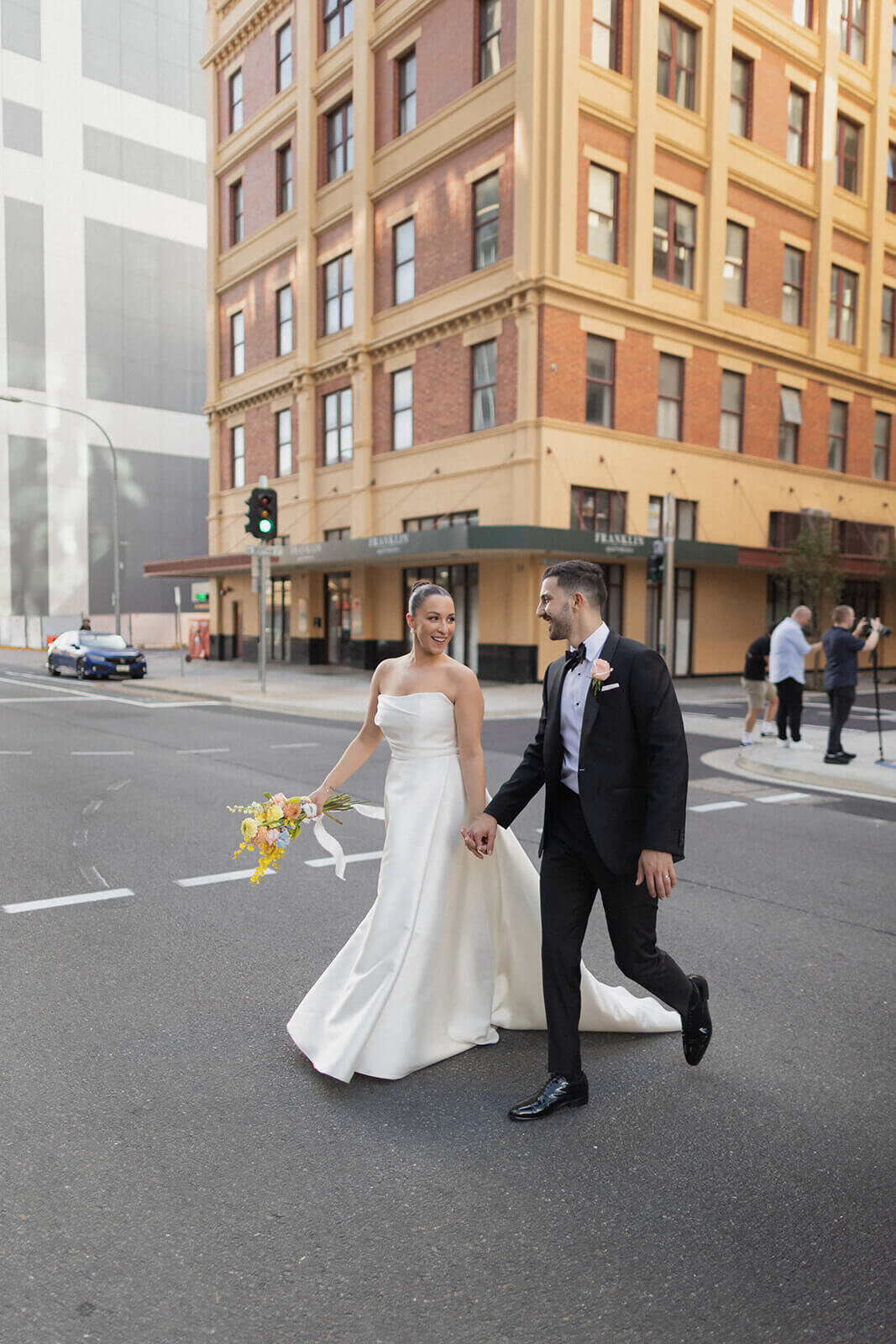 Bride and groom walking hand-in-hand smiling and relaxed.

