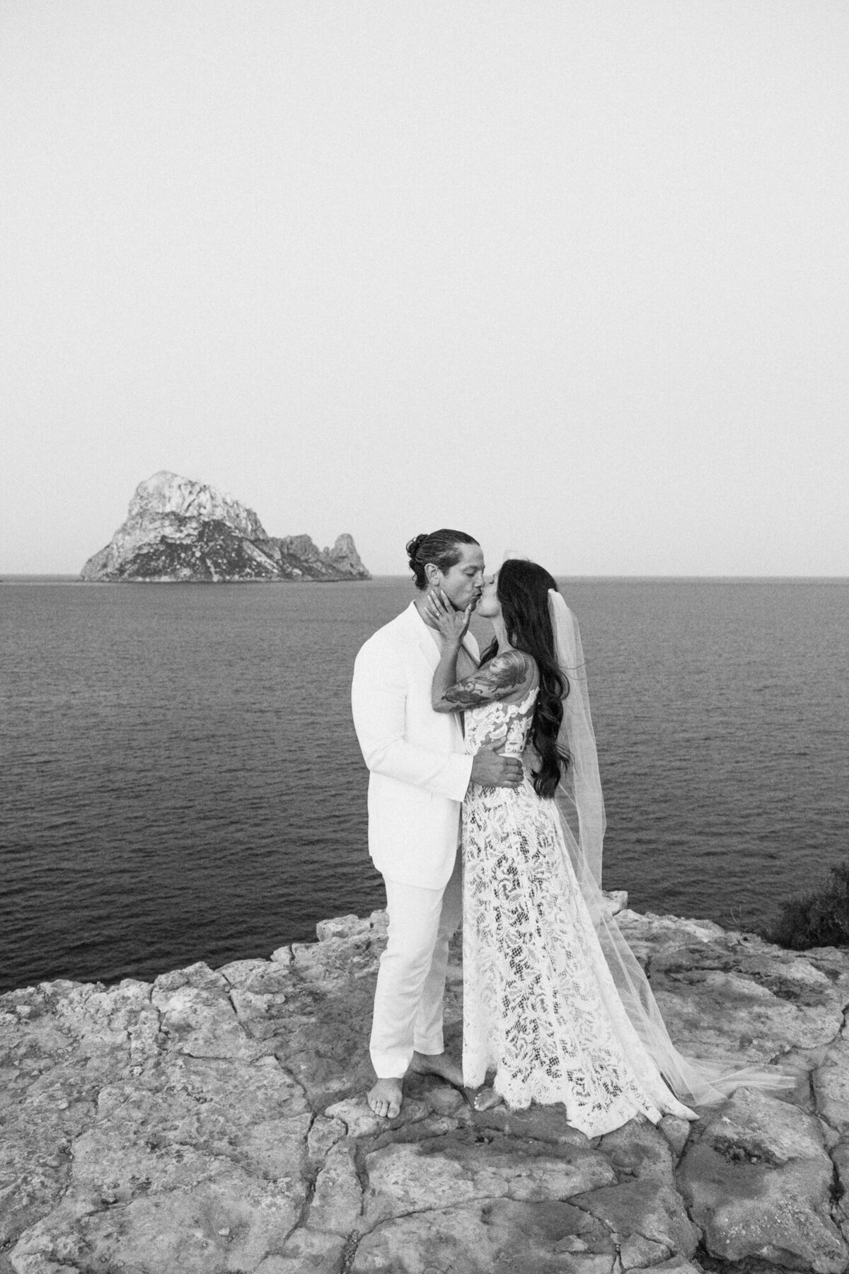 Bride and groom kissing each other in front of Es Vedra on Ibiza during a wedding photoshoot