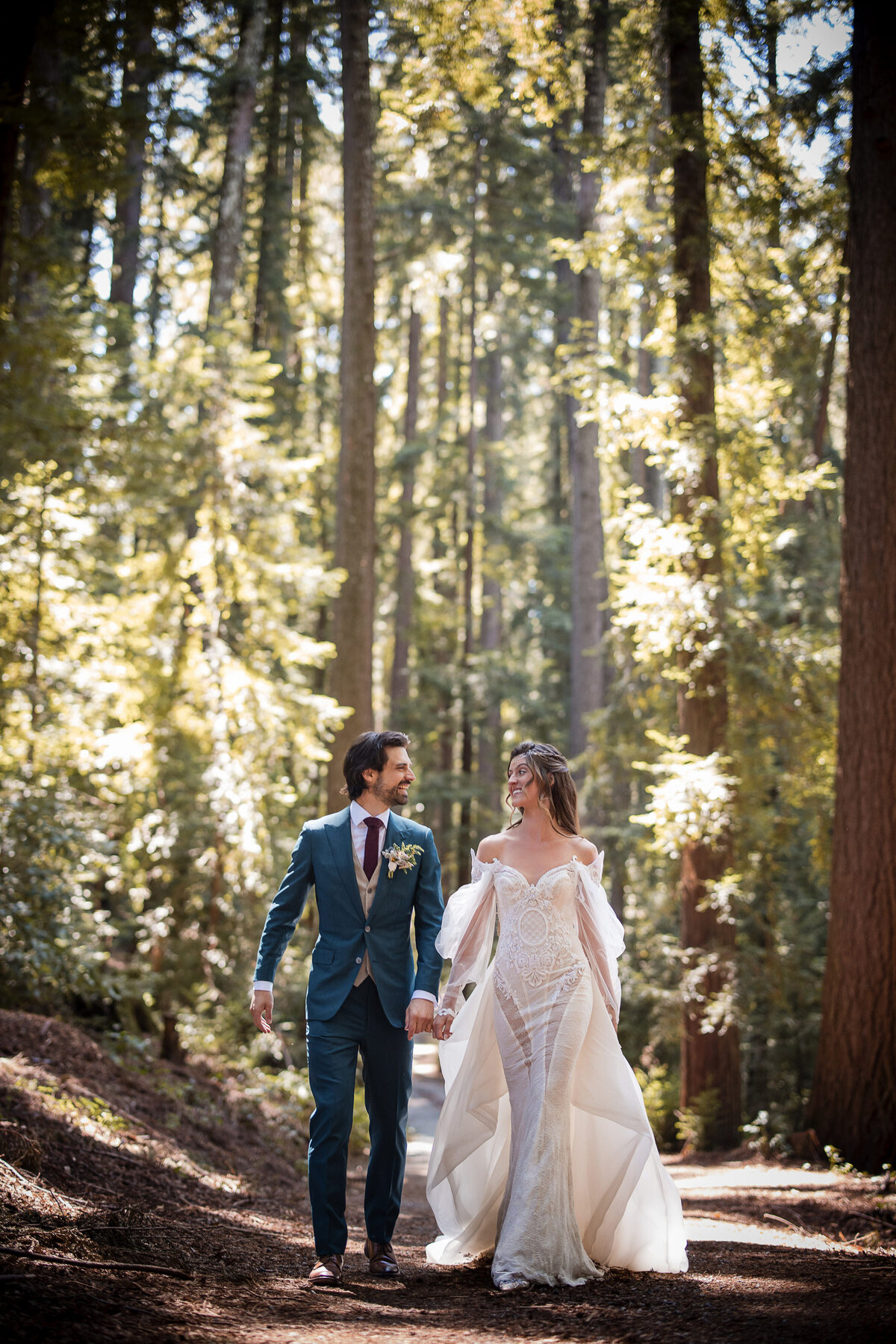 A couple walks through the redwoods hand in hand at a destination wedding at Nestldown in Los Gatos, California
