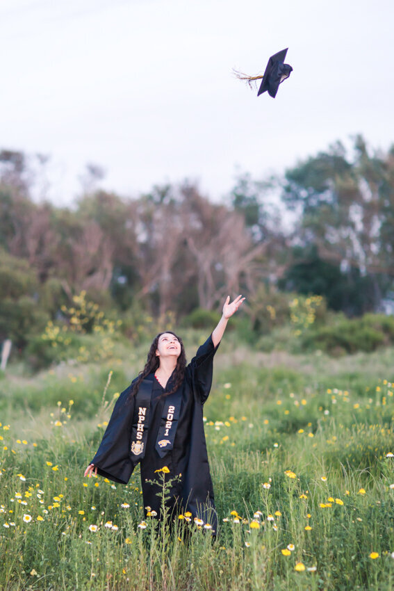 Senior girl tossing cap in field
