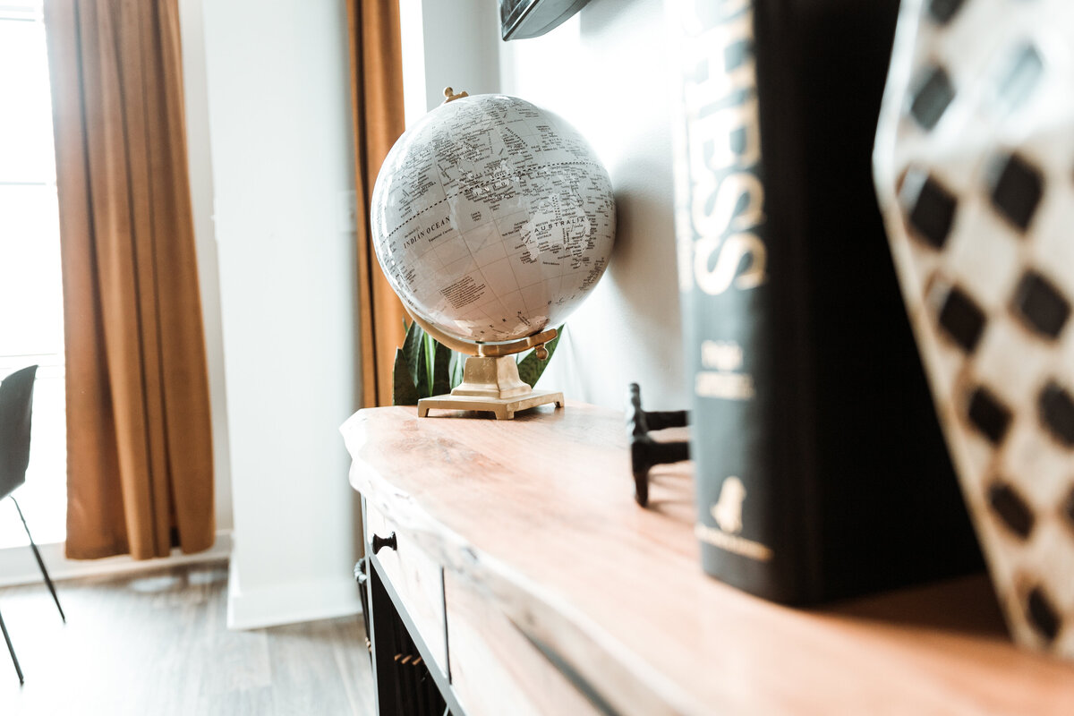 a desk with a globe, book, and vase on it