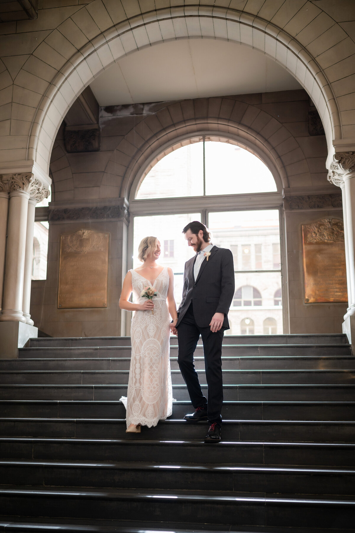 wedding couple walking down the staircase together at the allegheny county courthouse