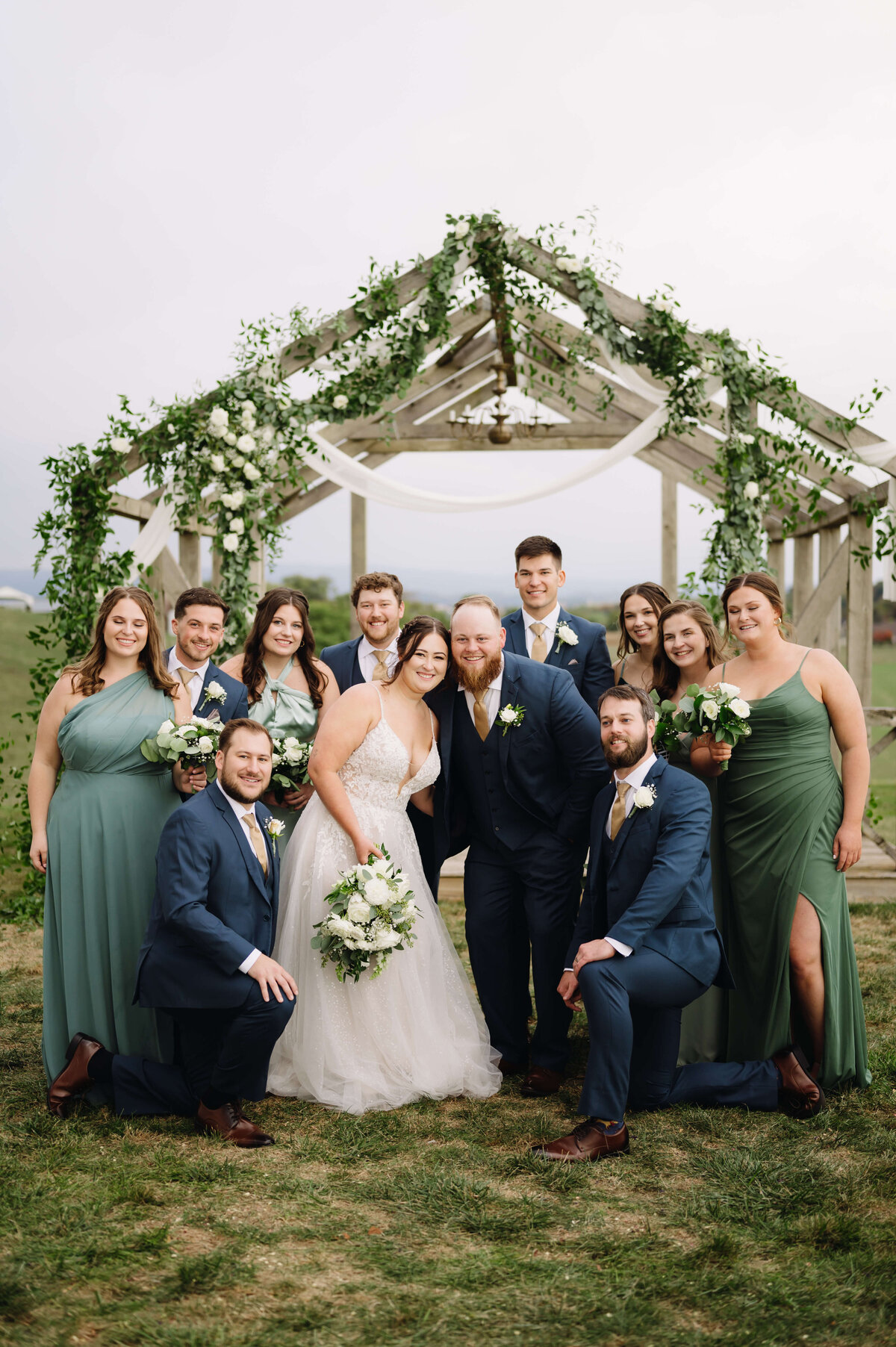 bridal party surrounds the bride and groom under a house frame decorated with florals and drapes for a Shenandoah National Park wedding