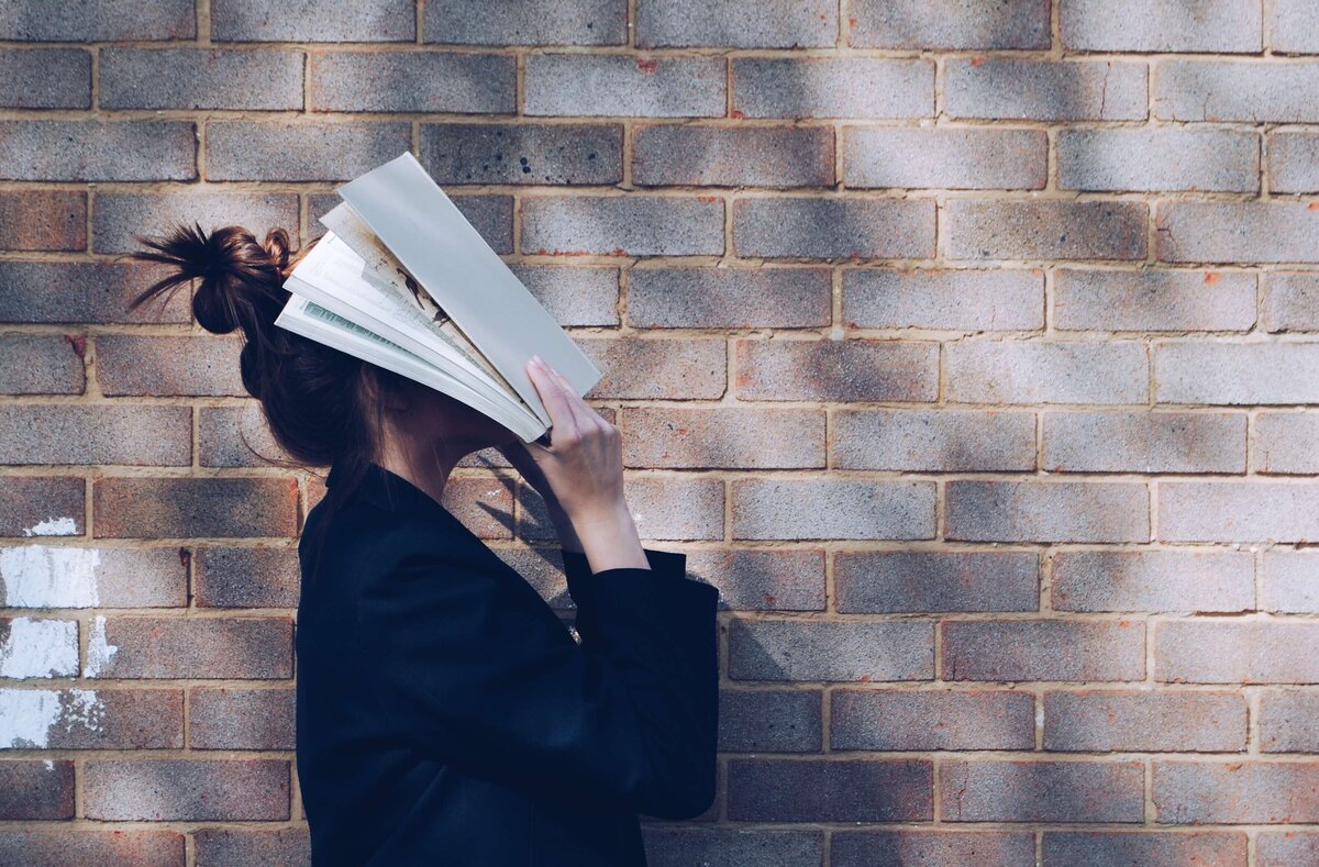 Overwhelmed student with book covering face