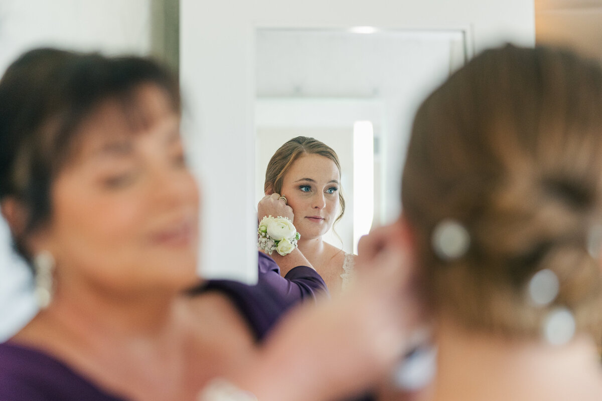 mother of the bride putting earrings on bride before wedding