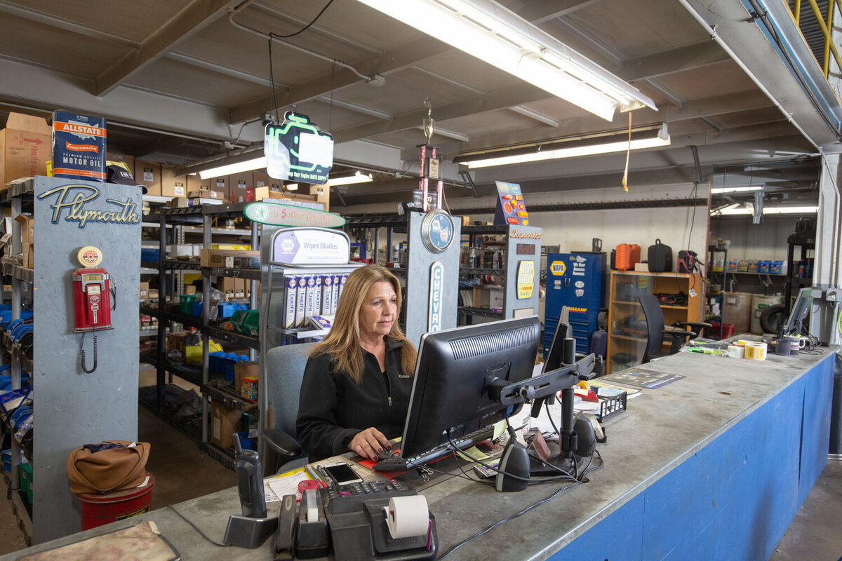 A woman sits at a desk in front of a computer in a store