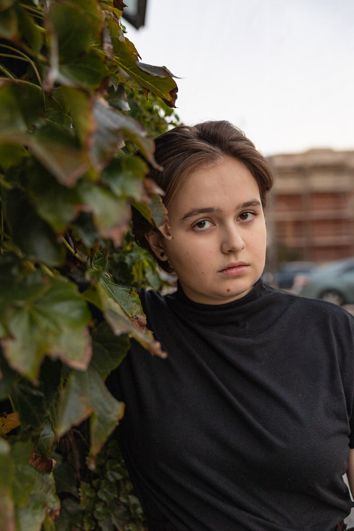 A senior girl leaning against a wall of ivy in downtown Lawrence KS