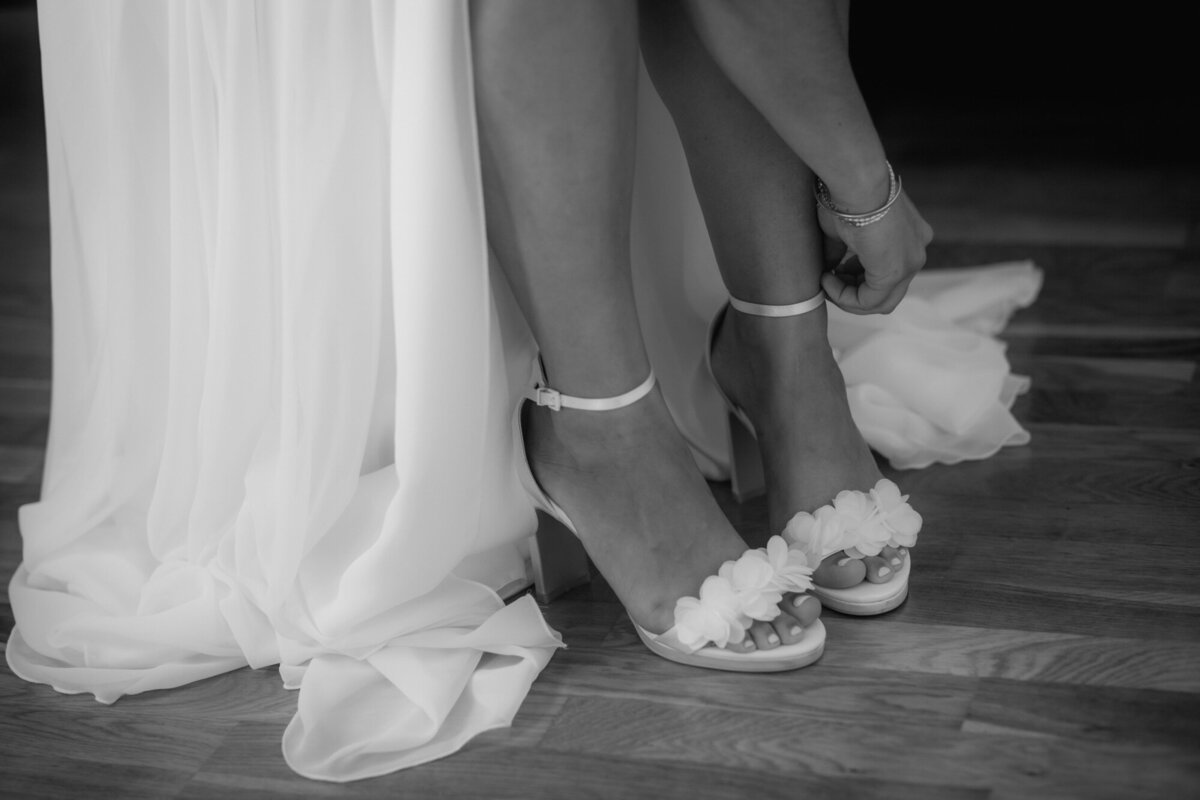 Die Braut schließt die Riemchen ihrer Peeptoe-Sandalen auf einer Nahaufnahme.