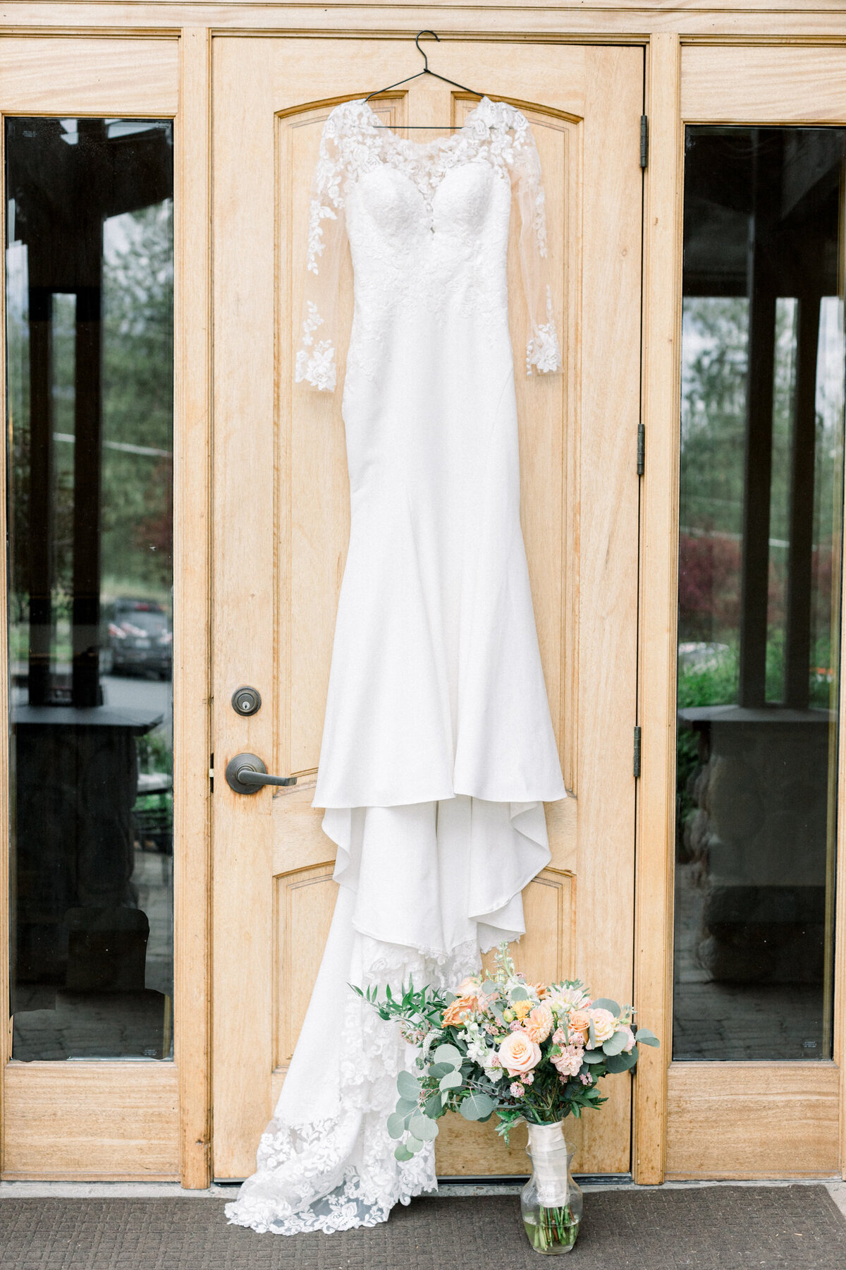 Brides dress hanging on a door with flowers and shoes taken by spokane wedding Photographer