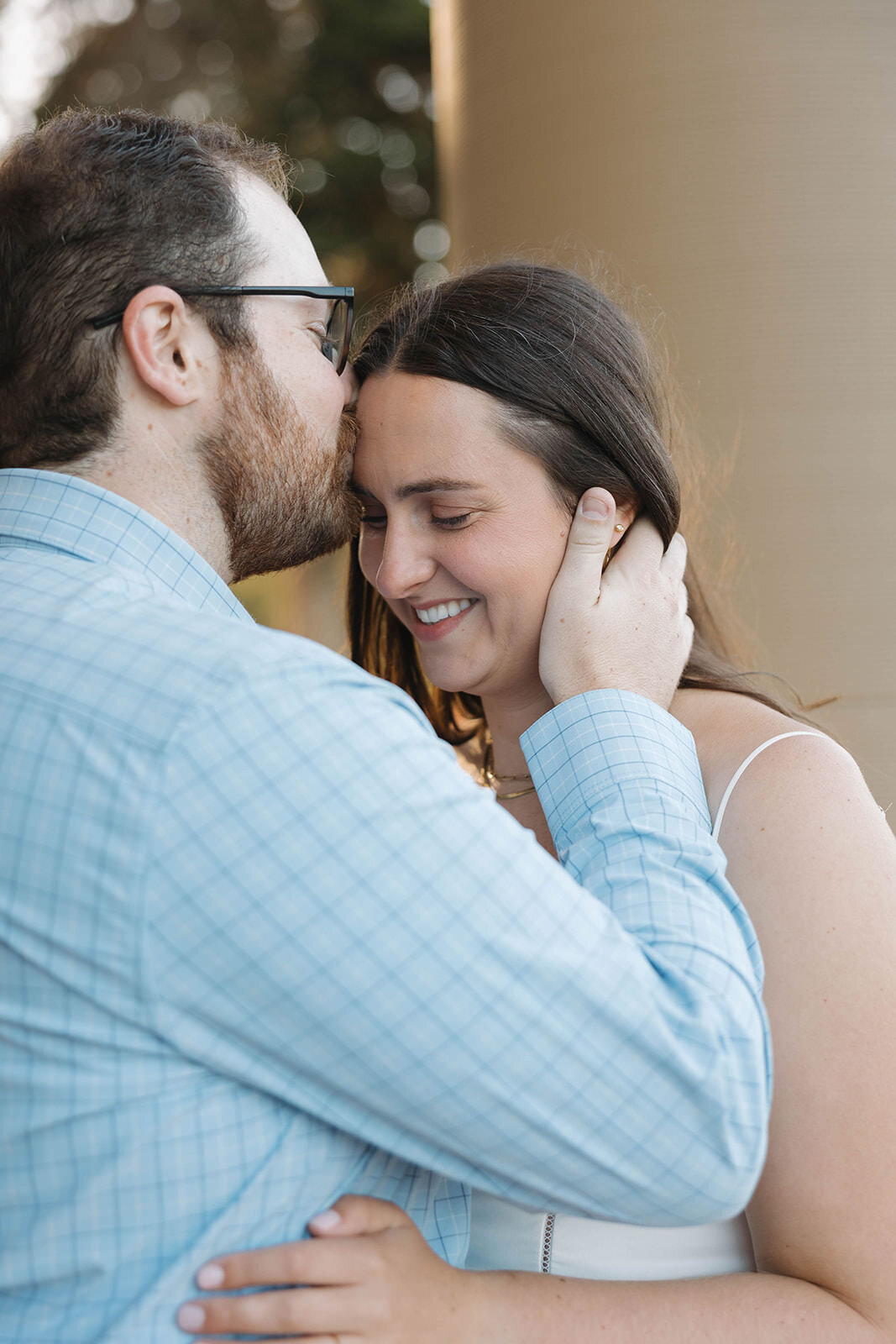 Groom to be kissing his fiancee on the forehead