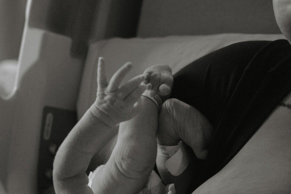 Black-and-white shot of a baby’s feet resting on the mother while nursing