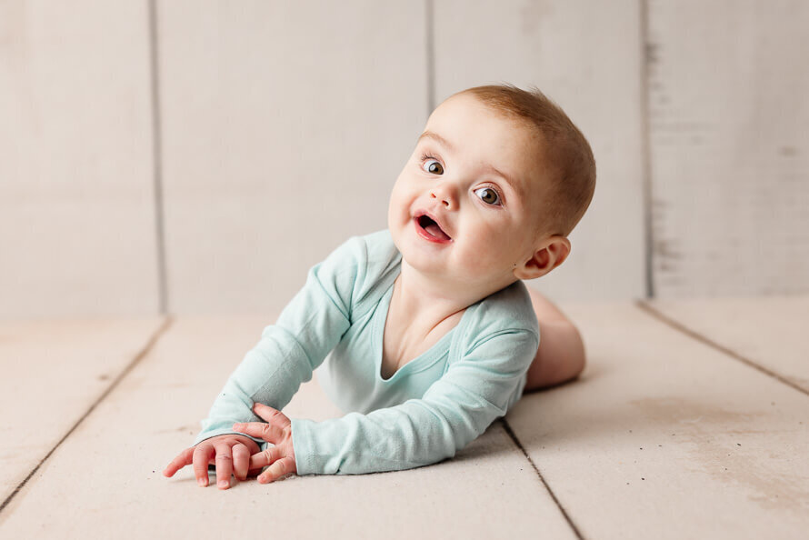 Baby boy in stomach smiles for camera for his one year photos.