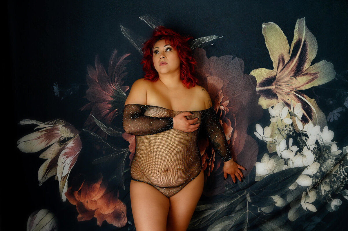 Woman wearing a black glitter bodysuit leaning against a flower background for her Toronto boudoir photos.