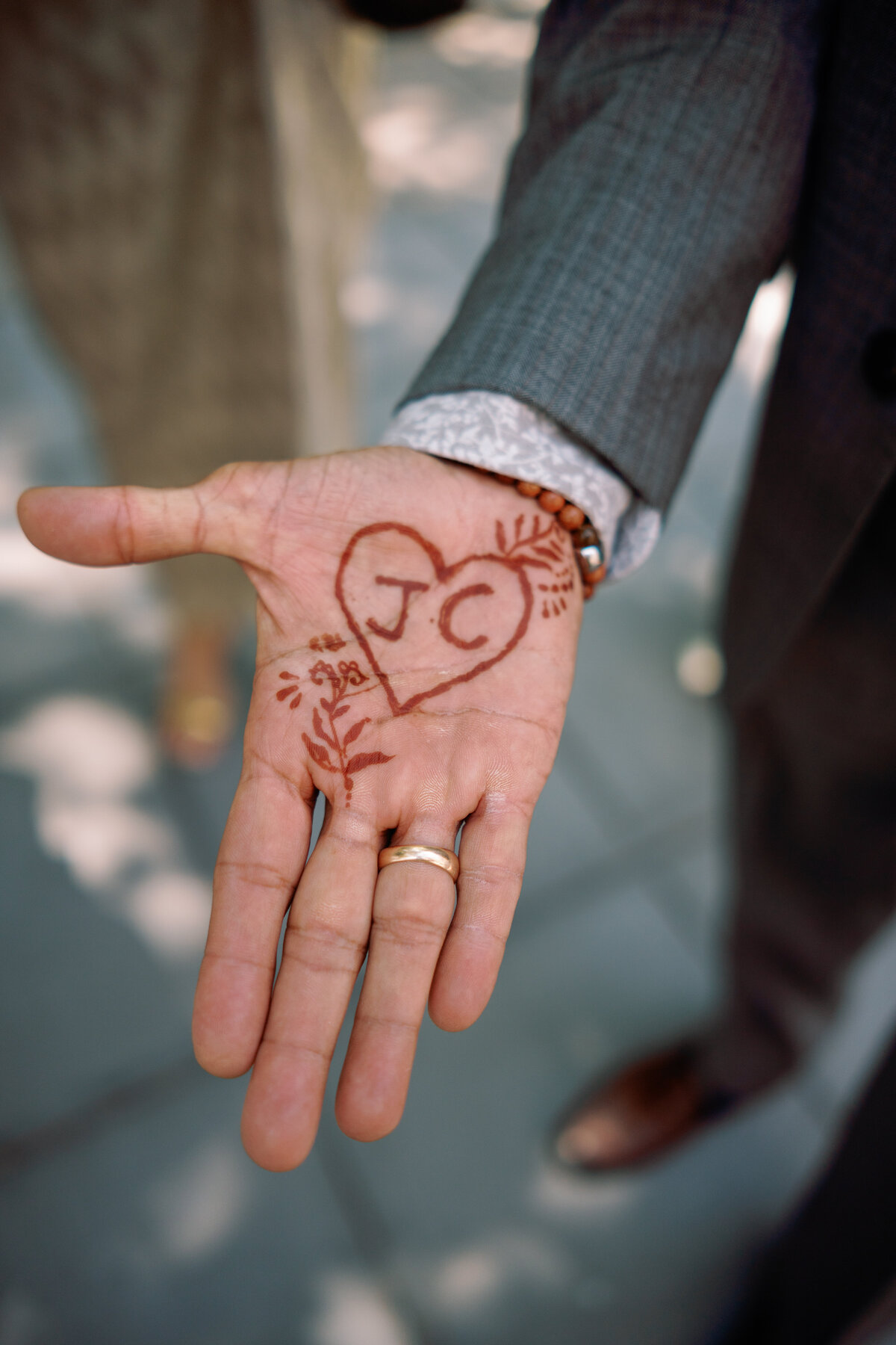 Close-up of a hand with henna design featuring the initials “J + C” in a heart, captured outside New York City Hall during Japna and Chris’s intimate elopement by NYC wedding photographer Perry Hancock.