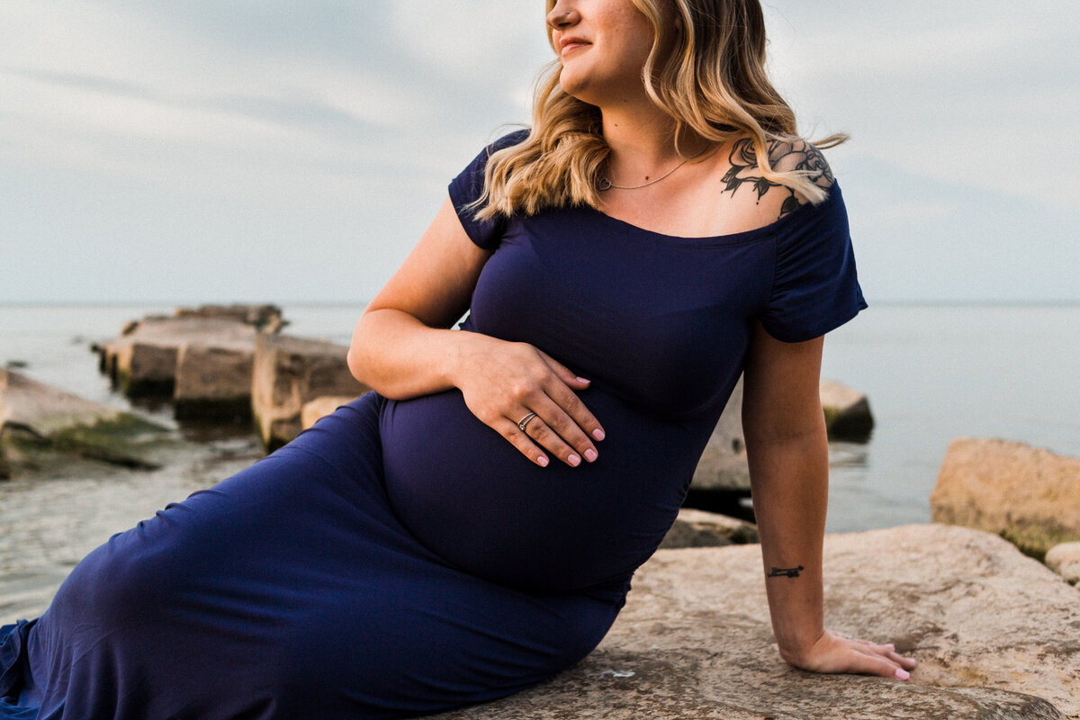 Mom caressing pregnant belly during maternity session at the beach in Cleveland, OH