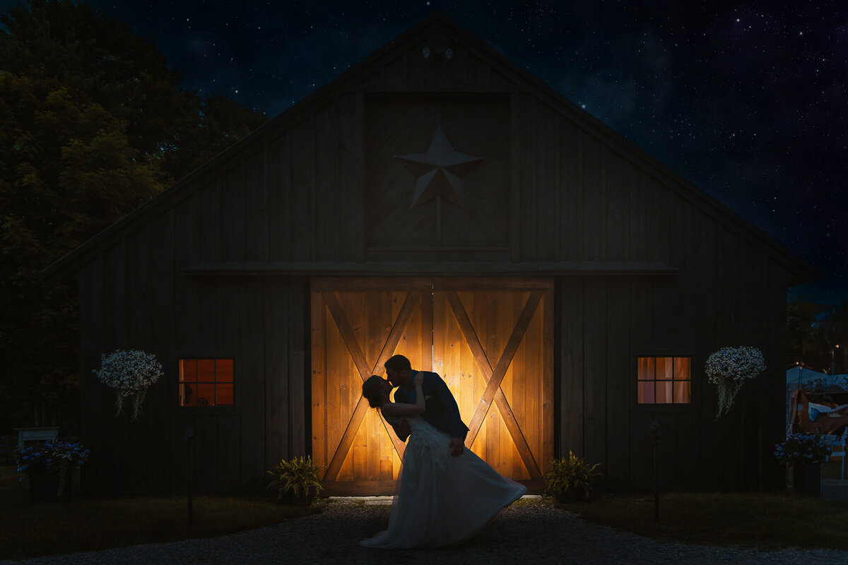 Bride dipping groom in front of barn doors at Mountain View Stables in Loudon NH
