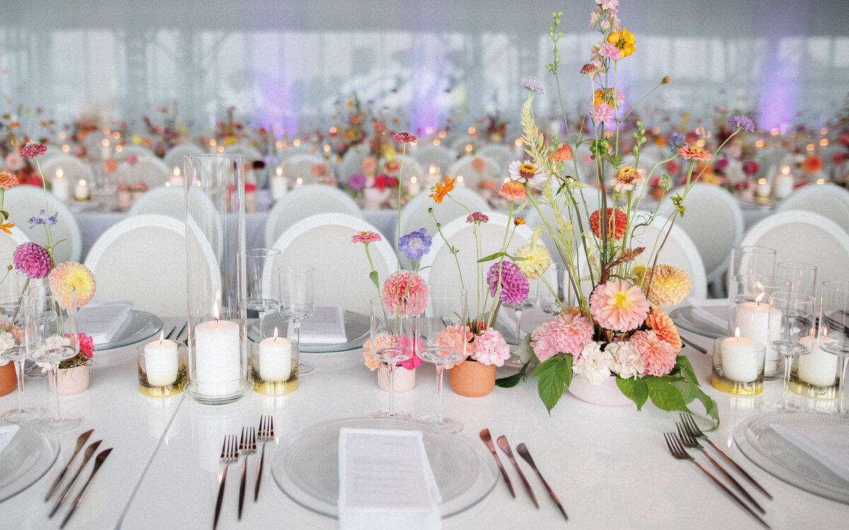 Tables at a Science Centre wedding reception decorated with colourful, whimsical floral centrepieces.