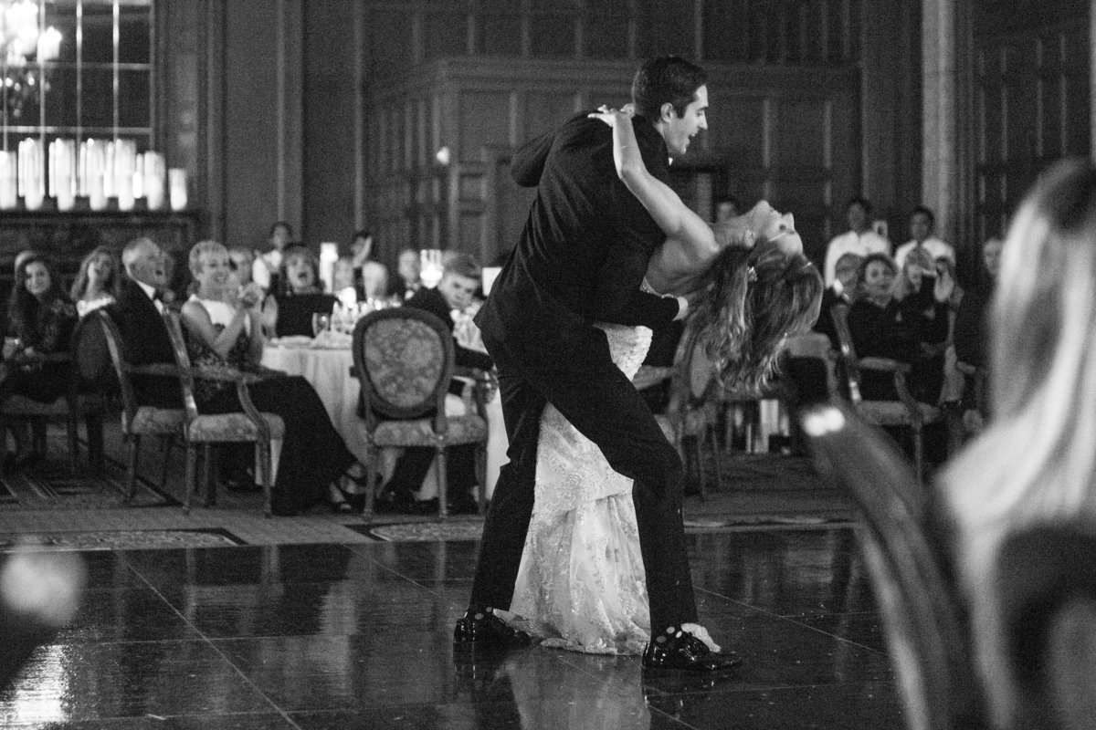 Just married couple dancing at their reception, groom dipping his bride, in black and white