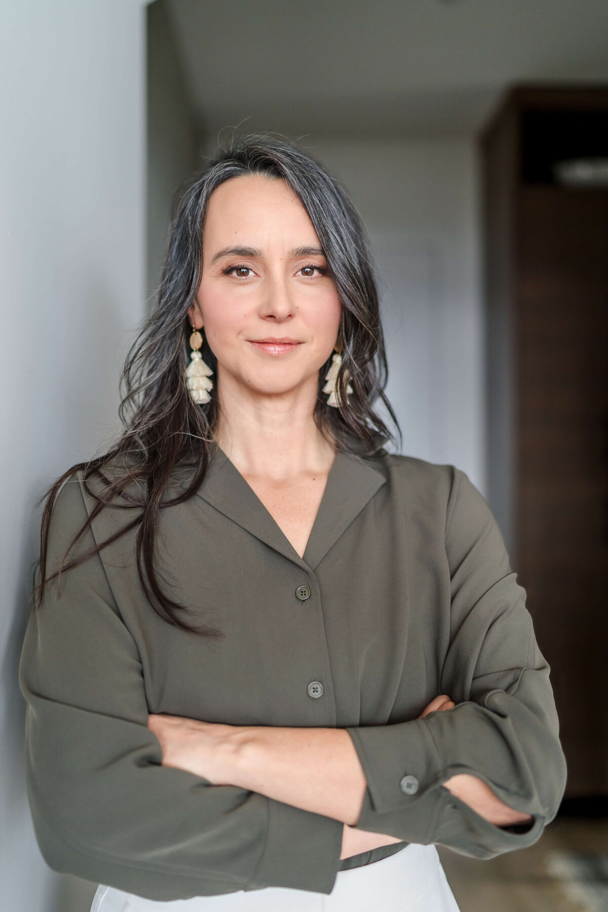 confident portrait of dark haired woman leaning on neutral wall