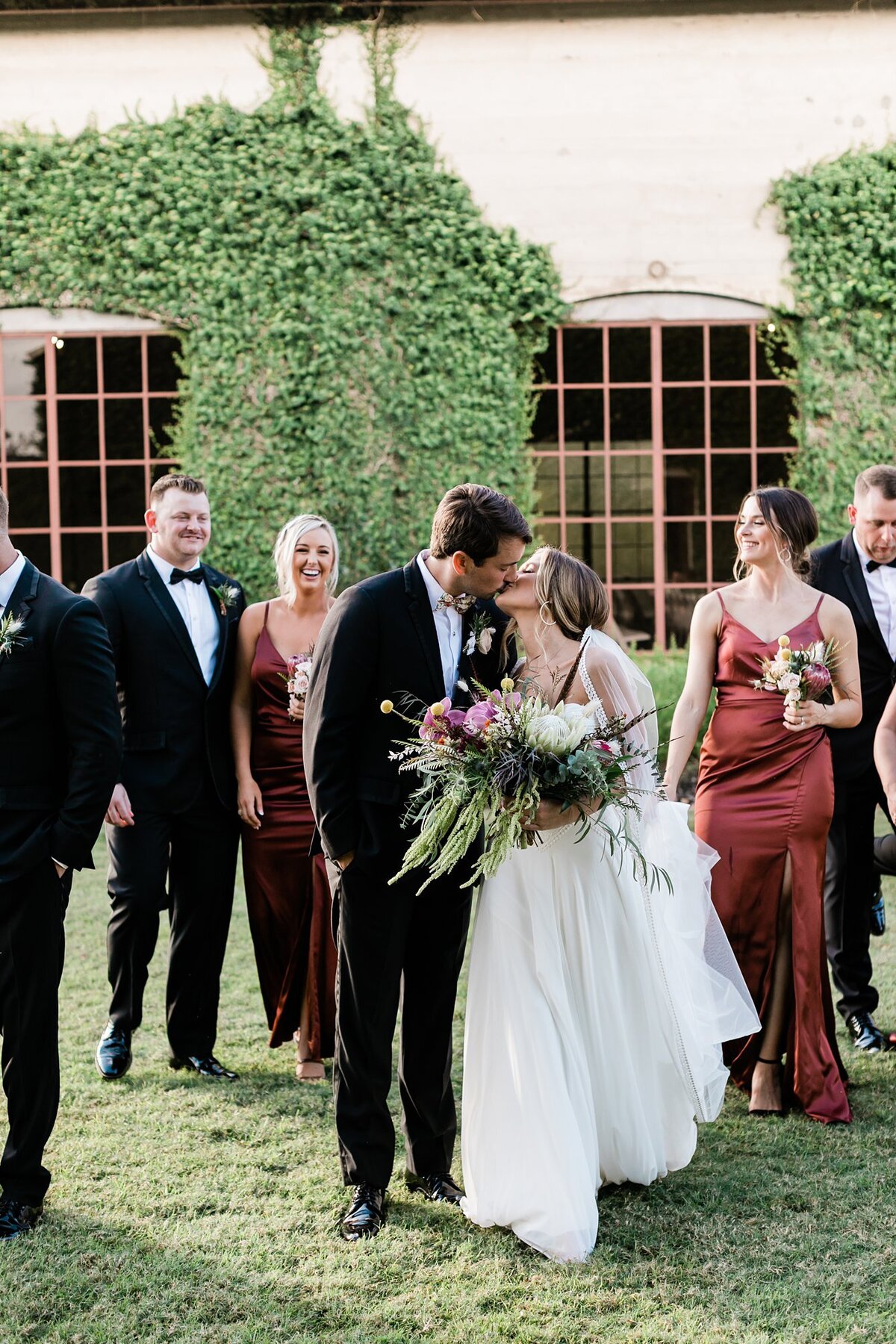 Bride and groom kissing while their wedding party cheers for them at Olde Dobbin Station