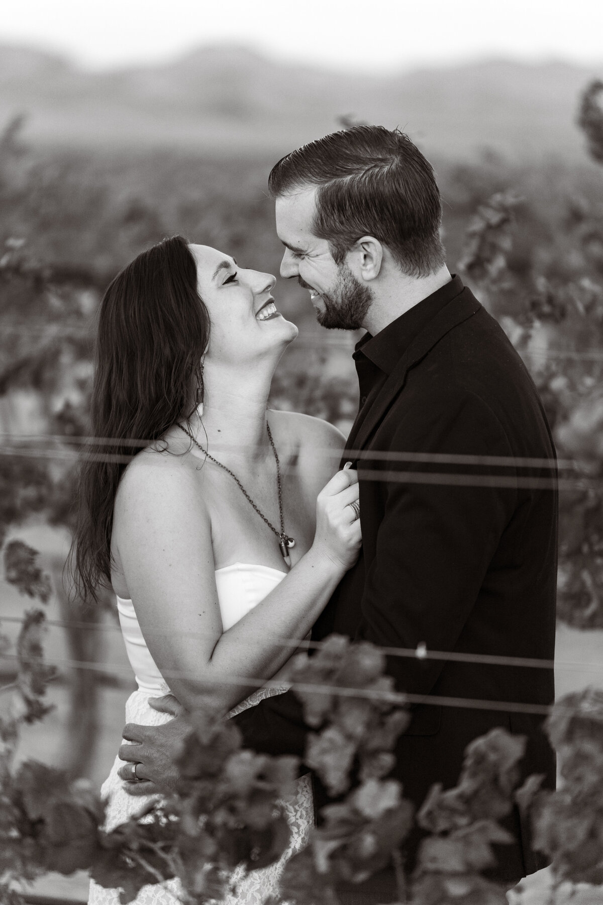 A couple about to kissing while standing in a vineyard