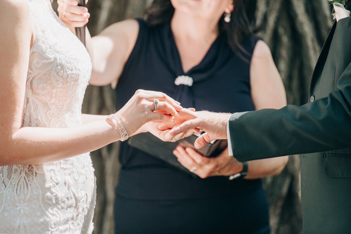 Bride and groom exchanging wedding rings during their outdoor Summer wedding ceremony