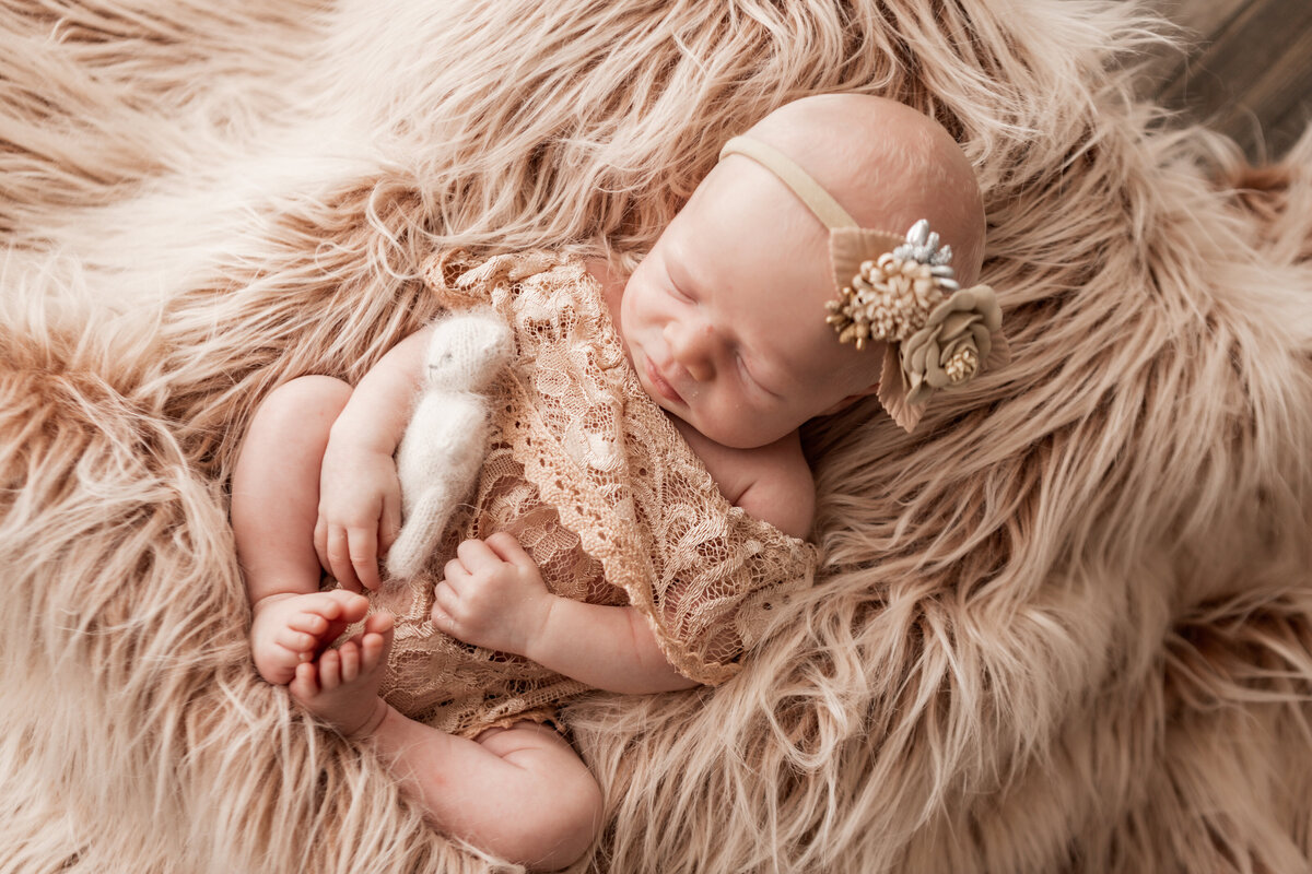 newborn in lace outfit on shaggy rug
