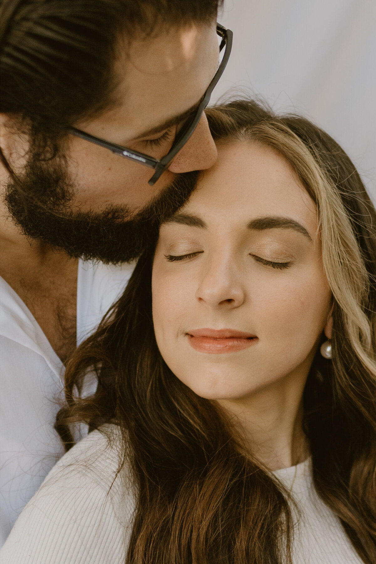 closeup photo of a man kissing his wife on the forehead.
