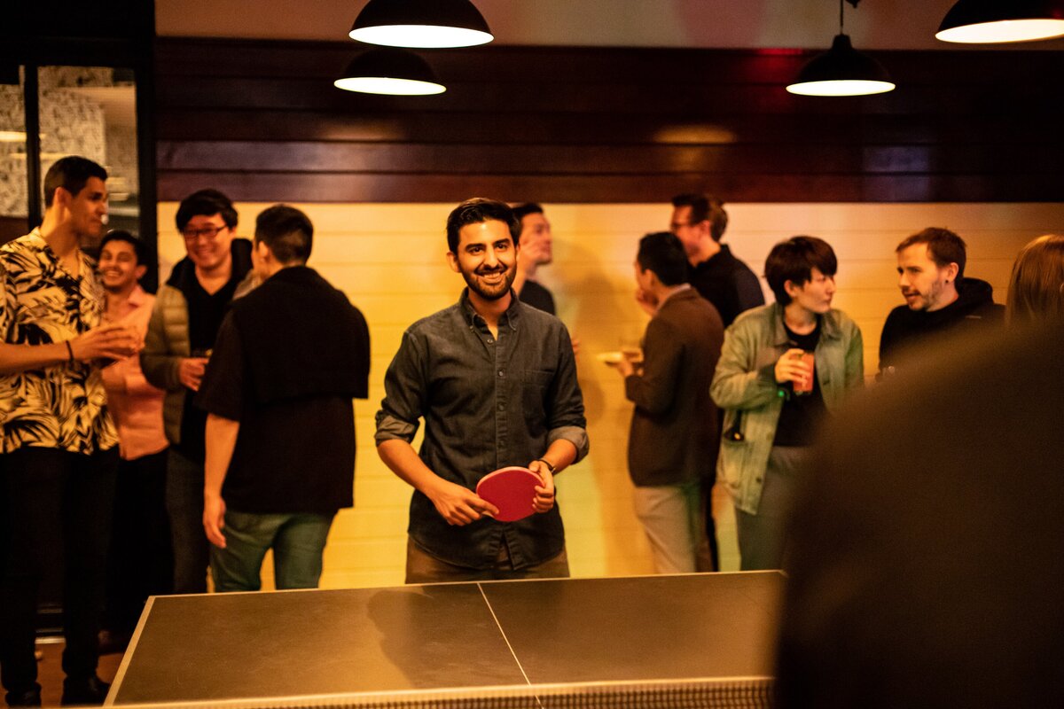 Guests socializing while an attendee plays ping-pong.