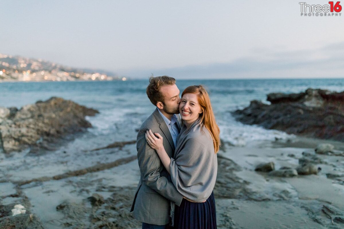 Groom to be whispers into his Bride's ear on the beach in Newport Beach