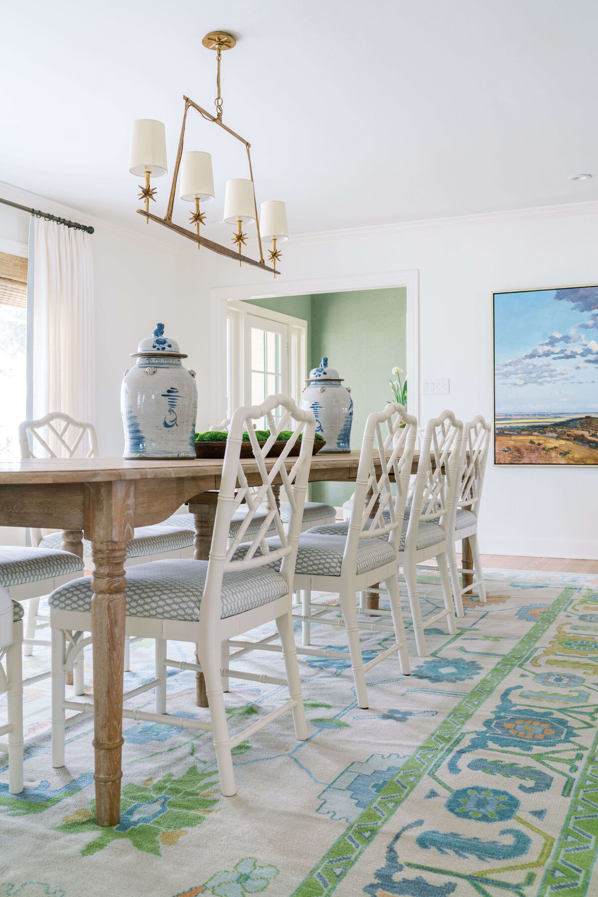 oyster creek studios happy valley white chairs around a wooden dining room table with white and green rug white tables surrounding a wooden coffee table with white light fixture in dining room