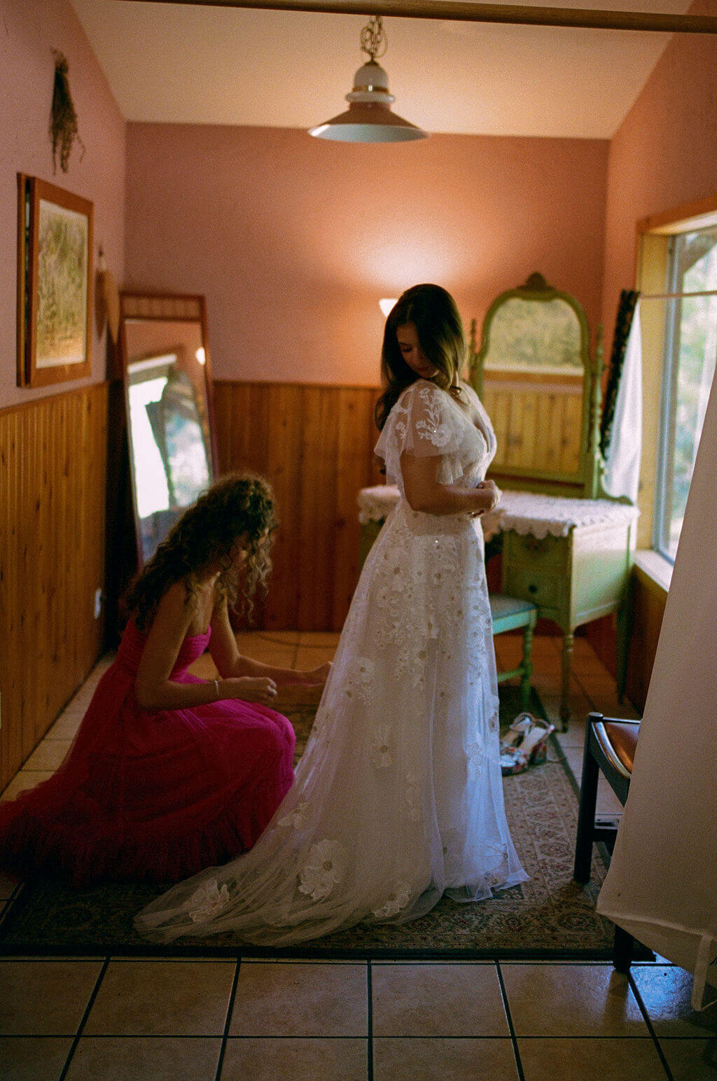 A bride getting her dress zipped up, representing the little moments she and her bridal party enjoy together.
