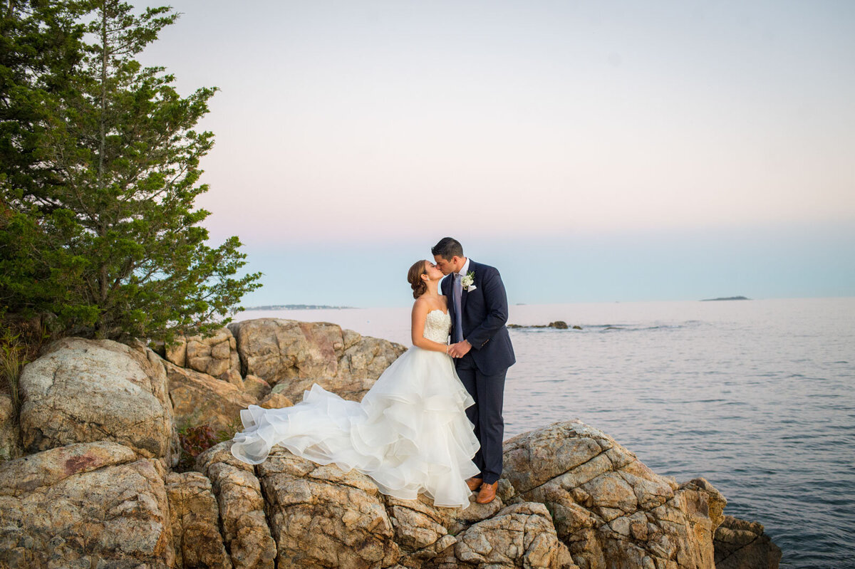 newlyweds kissing on rocks at misselwood at endicott college wedding