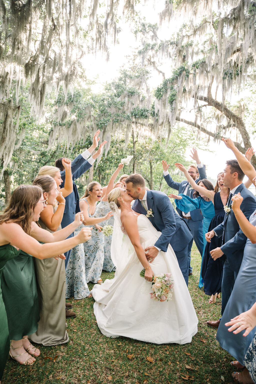 Bride and groom kissing while their bridal party cheers around them
