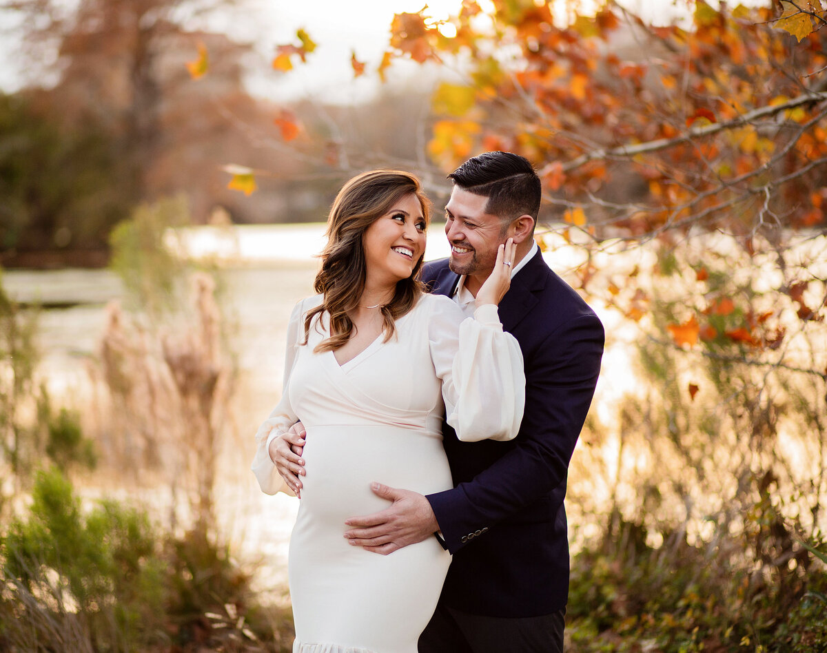 preganant mother holding dad's face at a beautiful location in San Marcos, Texas