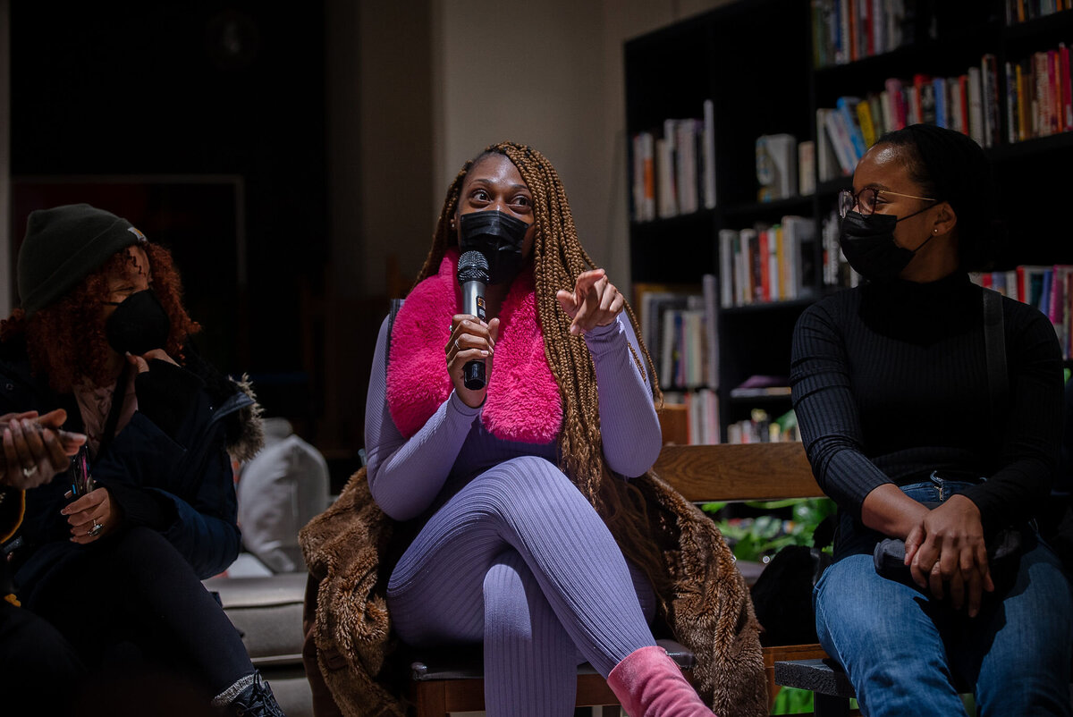 Person asking a question at Black Her Stories event, they are wearing a  mask