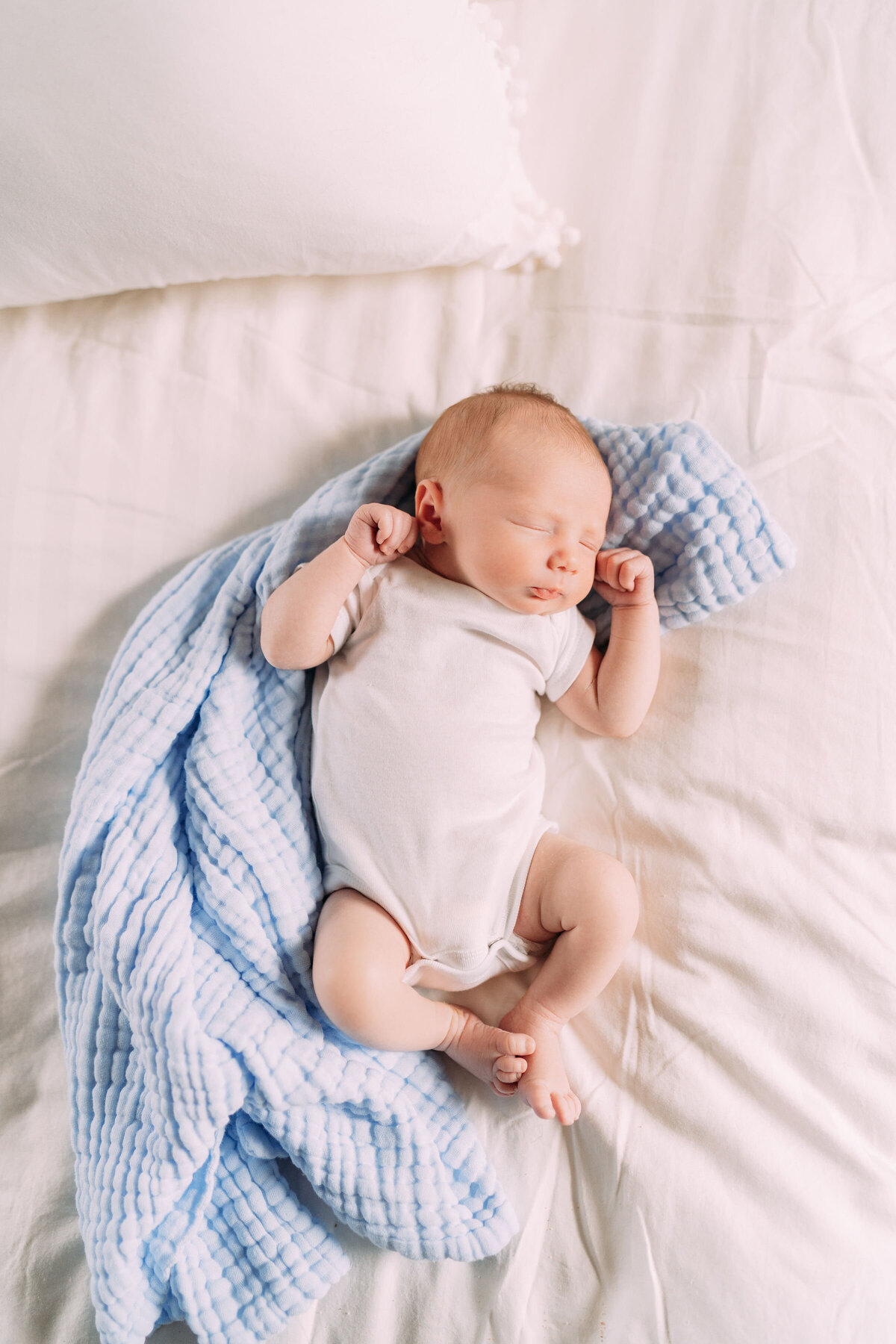 baby boy lays on blue swaddle on bed edmond oklahoma
