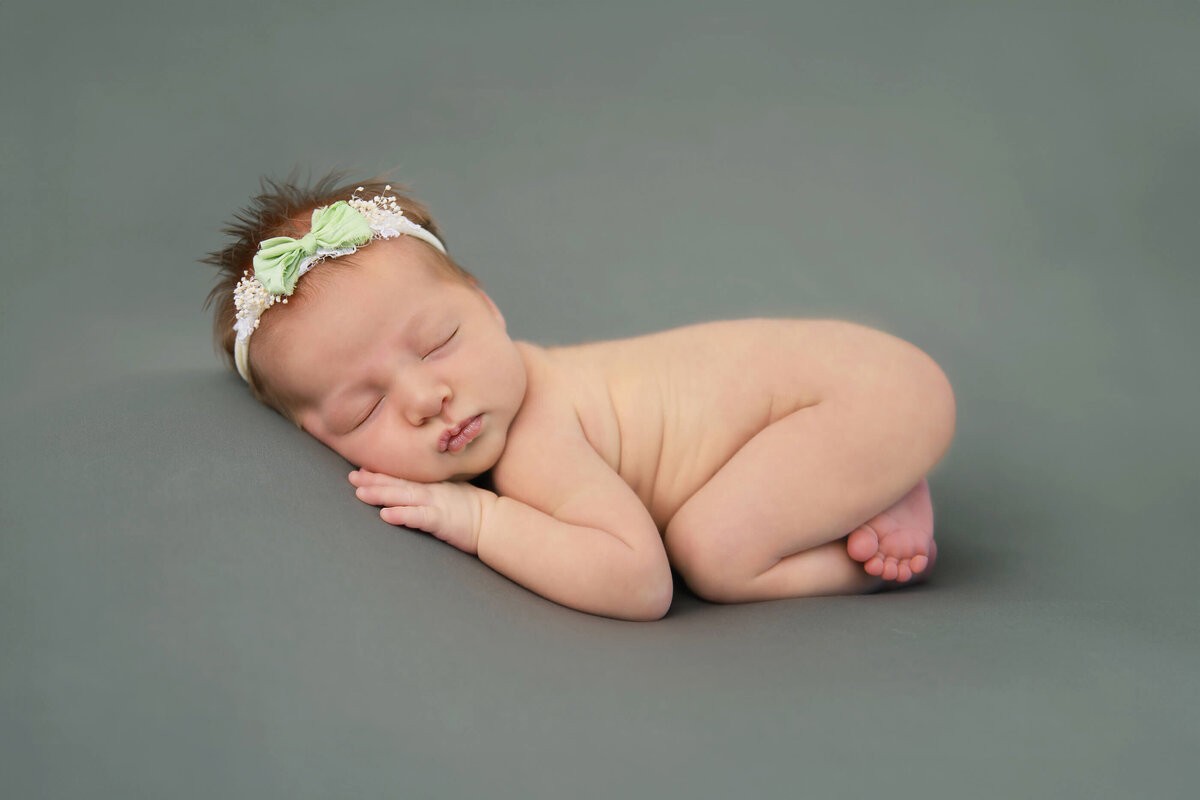 newborn girl on a green background for her newborn photos in Burlington, ON
