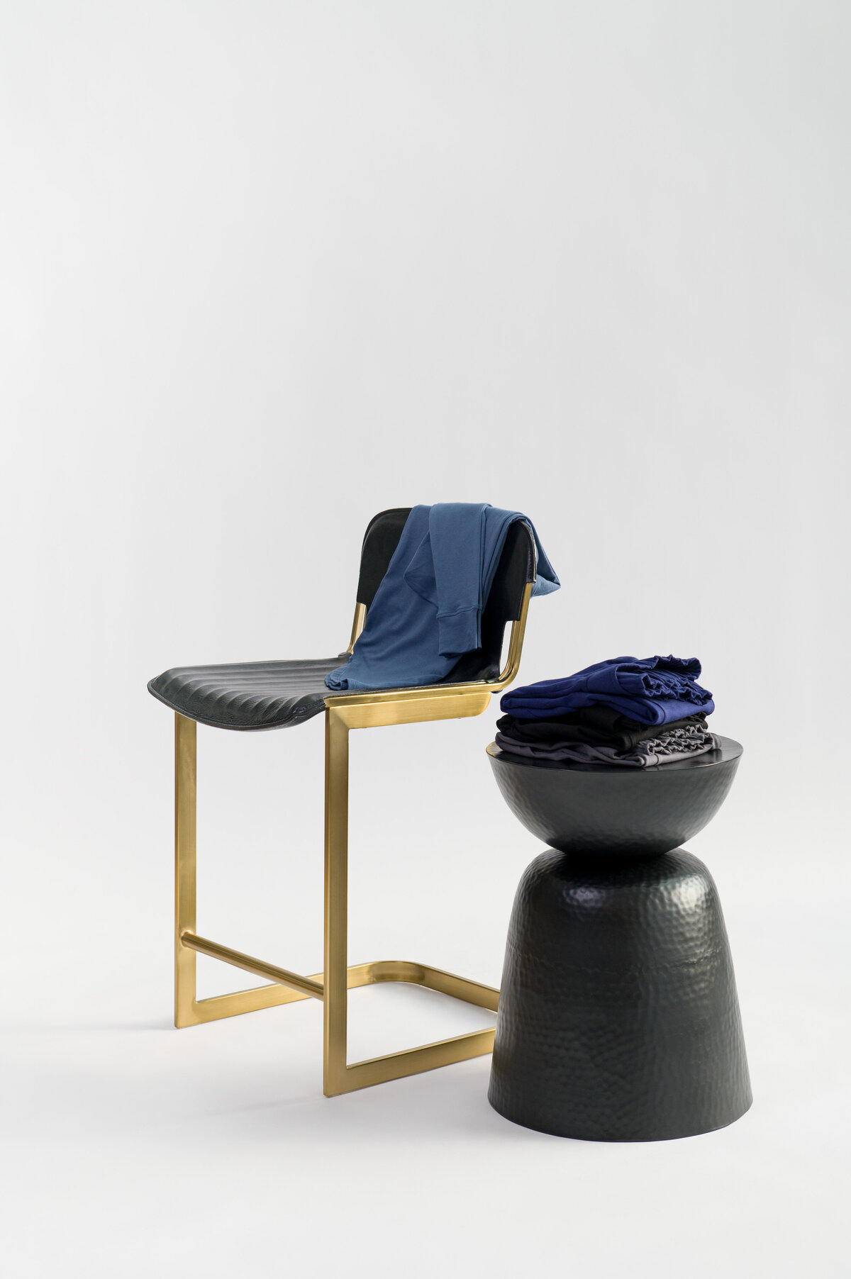Clothing folded sitting on gold and black leather chair and black table