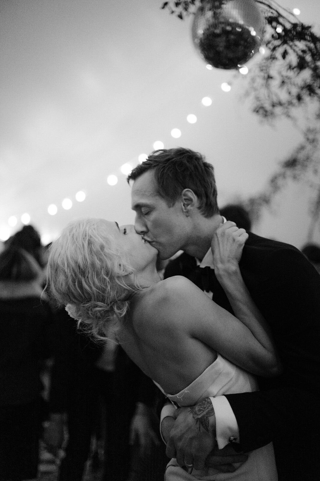 The bride and groom are romantically kissing each other on the dance floor in Foxfire Mountain House, New York. Wedding Image by Jenny Fu Studio